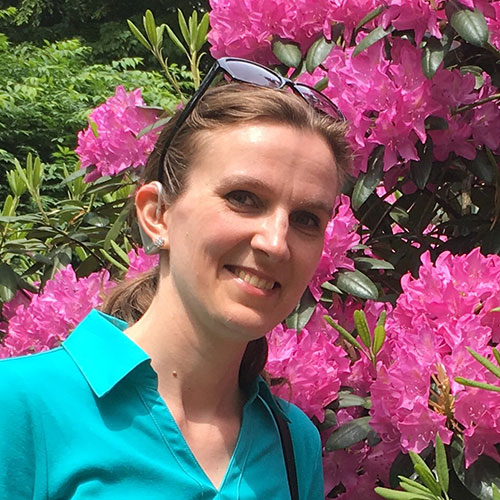 Svetlana Kouznetsova headshot in front of pretty pink flowers. 